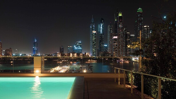 Panorama notturno di una città con area piscina.