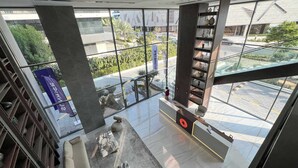 A modern interior with large windows, a marble coffee table, and a staircase with a railing.