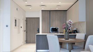 A modern kitchen with a central island, a dining area with a round table and chairs, and a microwave above the island.