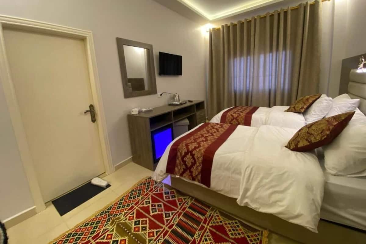 A hotel room with a bed, a desk, a chair, a television, and a door.