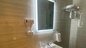 A modern bathroom with a glass shower enclosure, a built-in sink, and a hand dryer. - Petra Oleander Hotel (Wadi Musa)