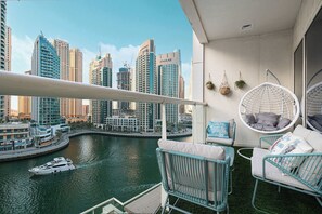 Un balcone con vista su un porto turistico e sullo skyline cittadino, con poltrone a dondolo e un tavolino.