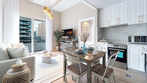 A modern kitchen with white cabinets, a dining table with chairs, and a large window overlooking a cityscape.