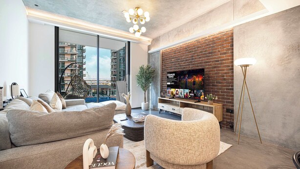 Ein modernes Wohnzimmer mit einer Couch, einem Sessel, einem Couchtisch und einem Fernseher an einer Ziegelwand.