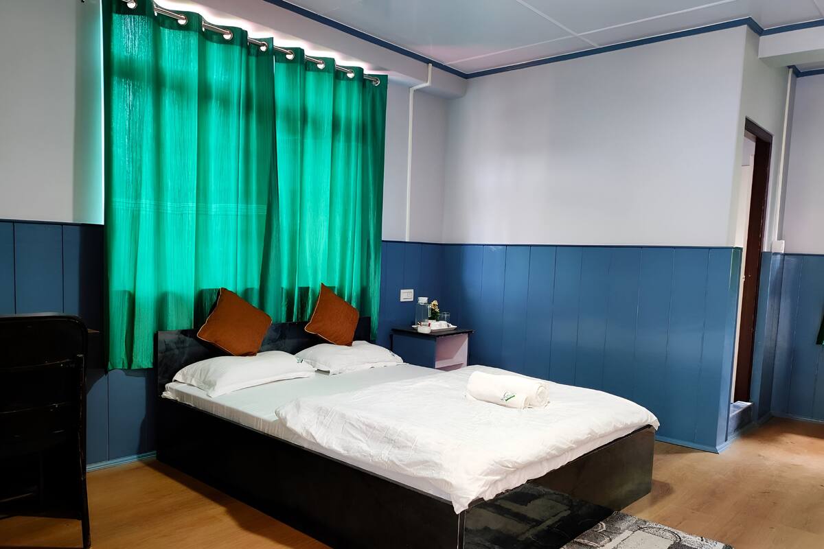 A bedroom with a bed, a nightstand, and a chair.