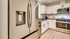 Una cucina moderna con elettrodomestici in acciaio inossidabile, mobili bianchi e forno integrato.