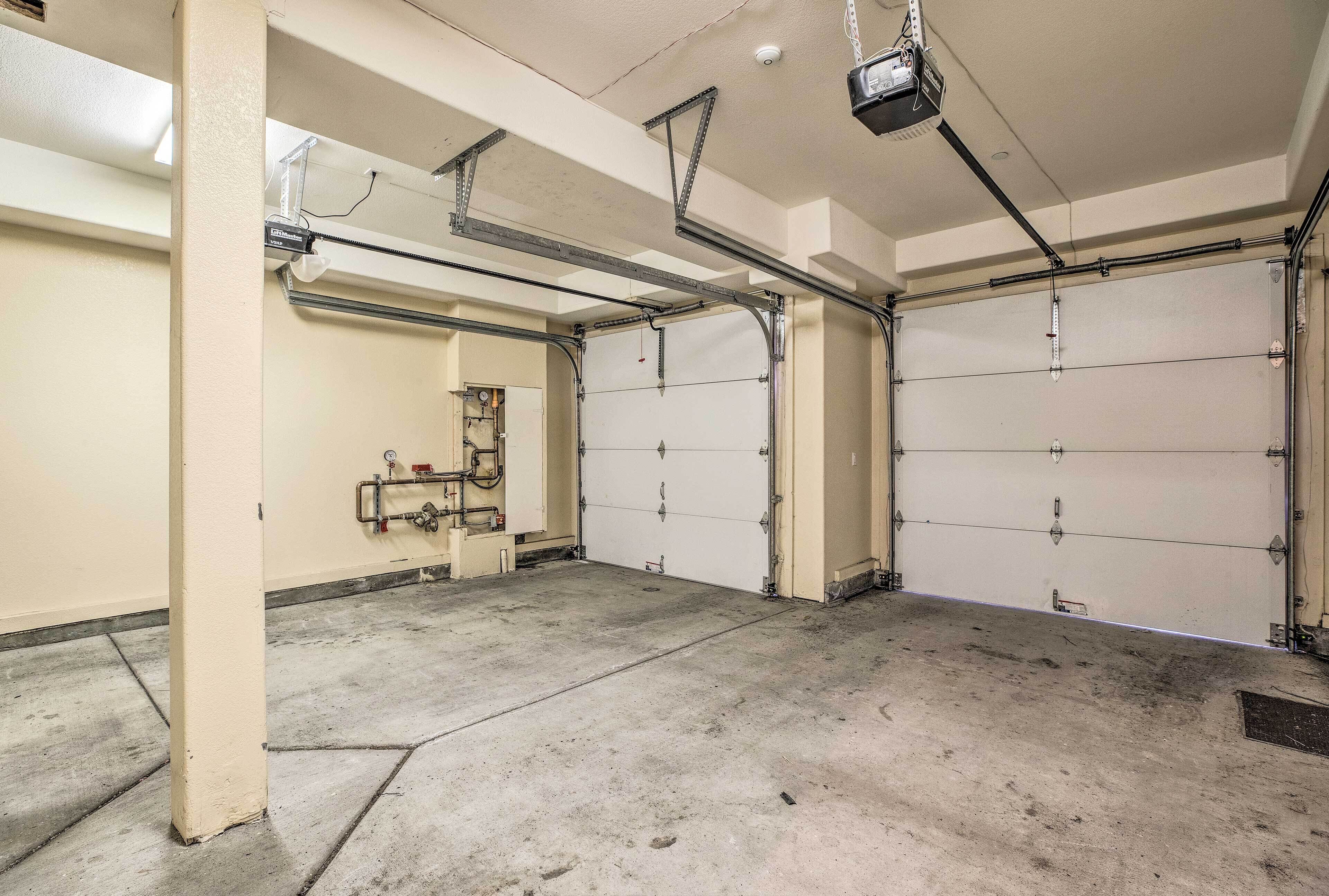 Un garaje limpio y vacío con dos grandes puertas de garaje, piso de concreto y tuberías y sistemas eléctricos a la vista.