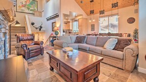 A spacious living area with a large sectional sofa, a leather armchair, and a wooden coffee table. A staircase with a wooden railing leads to an upper level. - Mammoth Lakes Townhome - 10-min Walk to Village! (Mammoth Lakes)