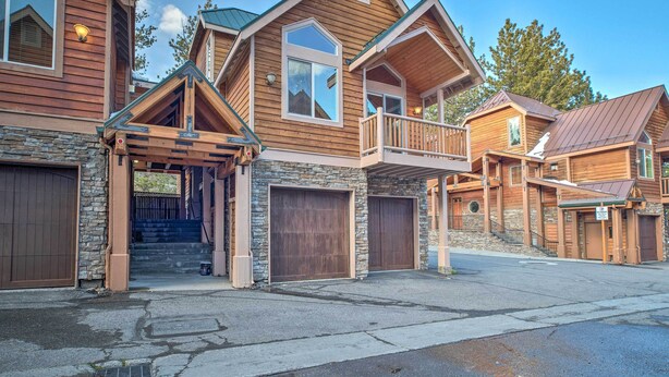 A multi-story wooden house with a stone foundation, large garage doors, and a balcony. - Mammoth Lakes Townhome - 10-min Walk to Village! (Mammoth Lakes)