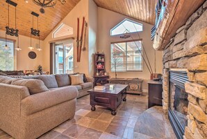 A spacious living room with a large sofa, a wooden coffee table, and a stone fireplace.