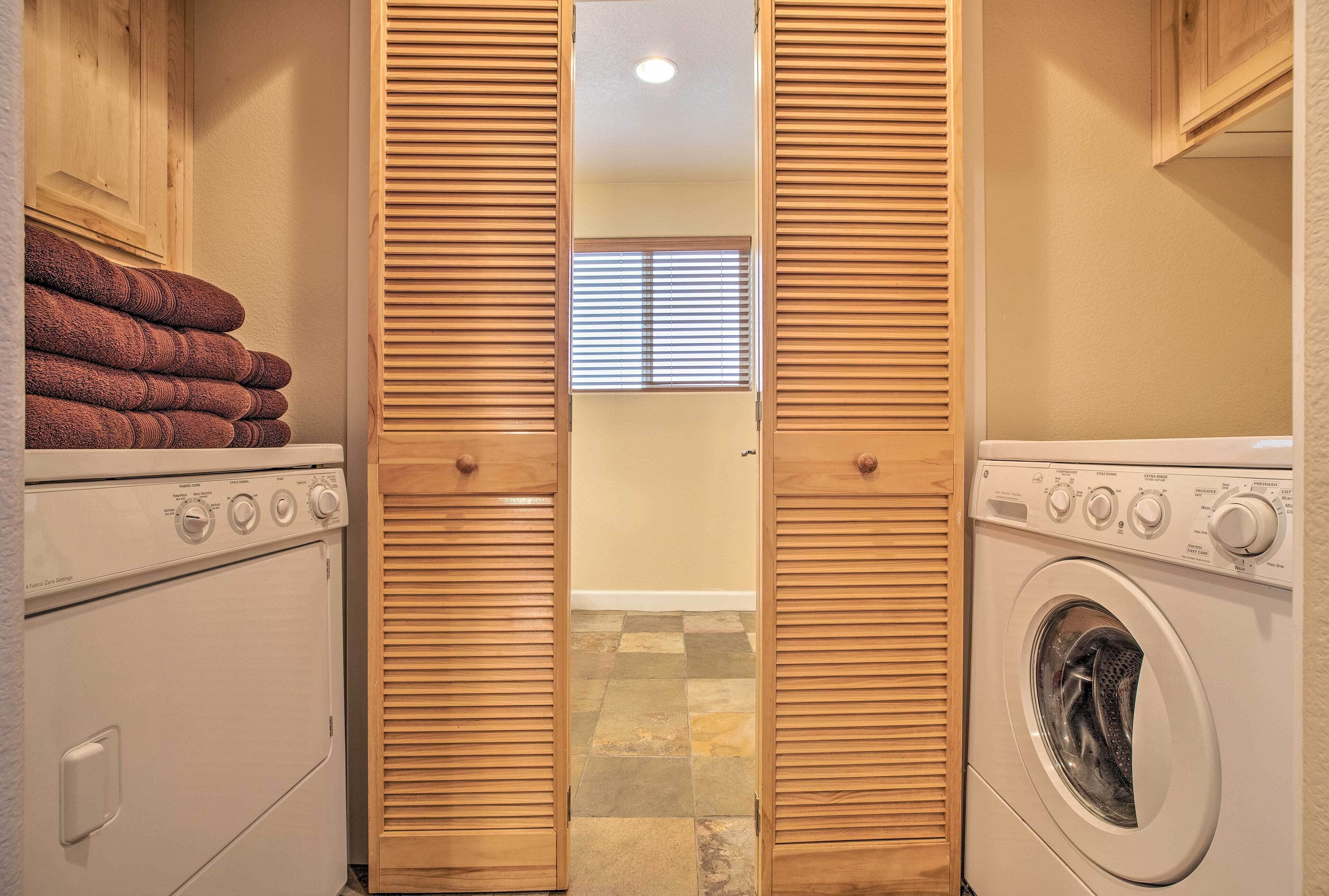 A laundry room with two washing machines, wooden cabinets, and a tiled floor.