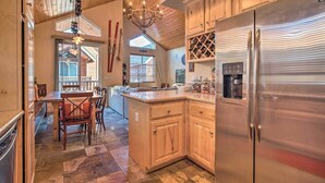 A spacious kitchen with wooden cabinets, a stainless steel refrigerator, and a dining area with a wooden table and chairs. - Mammoth Lakes Townhome - 10-min Walk to Village! (Mammoth Lakes)