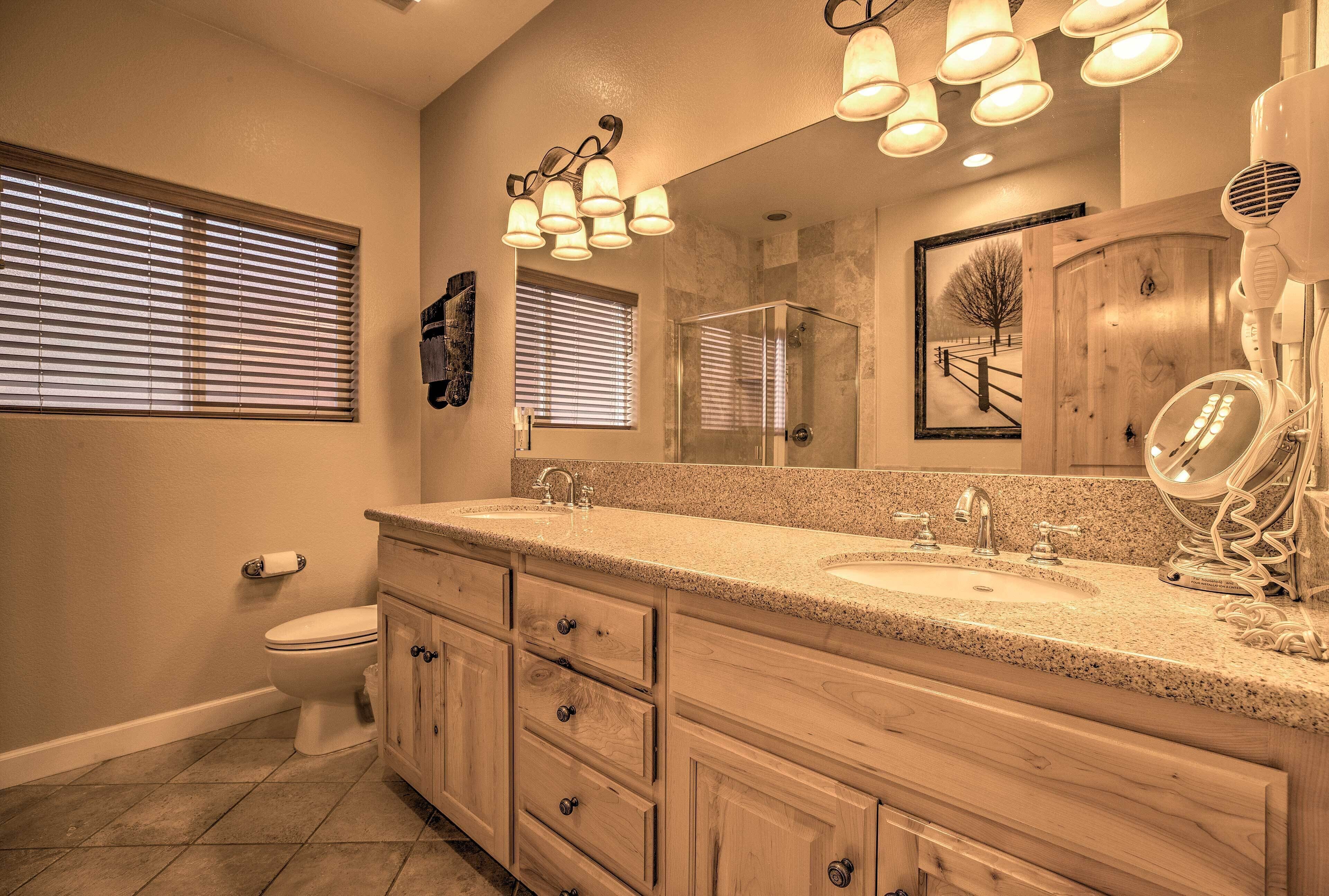 A bathroom with a double sink vanity, a glass shower enclosure, and a large mirror with lights.