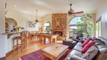 A spacious living room with a fireplace, a pool table, and a leather sofa.
