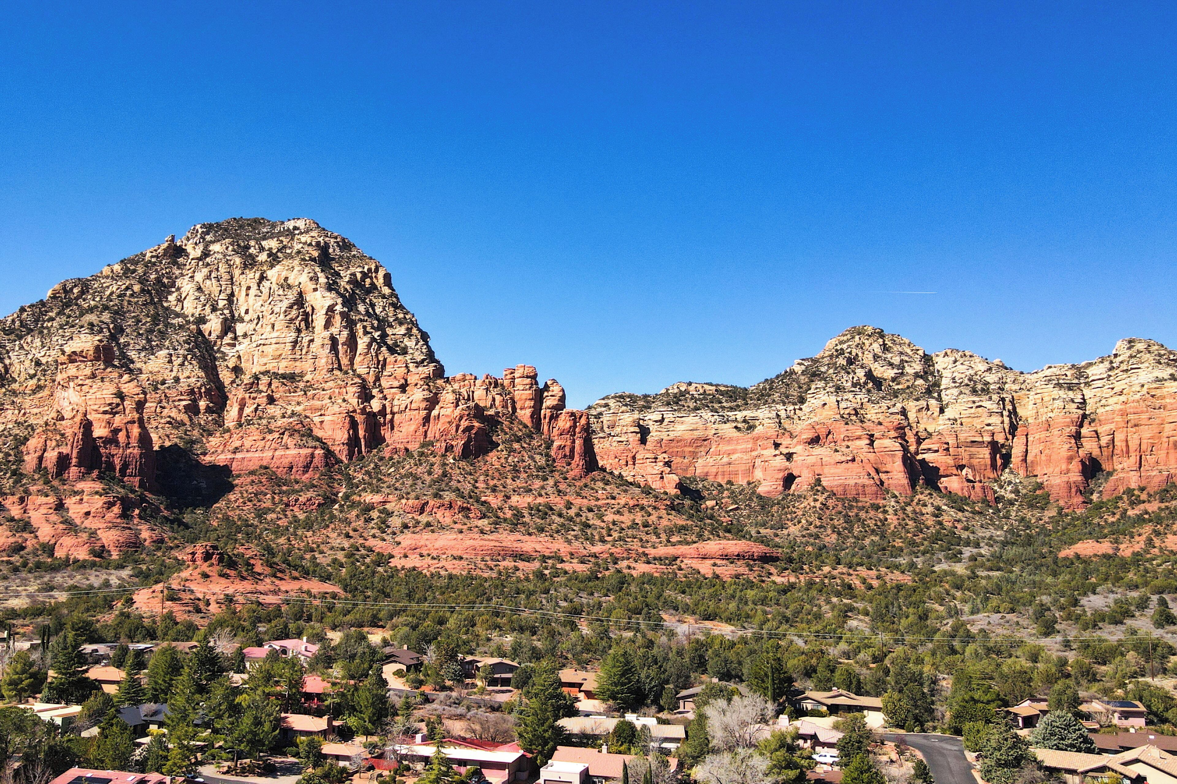 A town with houses and a prominent red rock mountain in the background.
