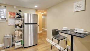A modern kitchen with a stainless steel refrigerator, a hanging rack with kitchen towels, and a dining table with chairs. - 1 Mi to Dtwn Wilmington: Convenient + Cozy Home! (Wilmington)