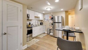 A compact kitchen with white cabinets, a stainless steel refrigerator, and a dining area with a table and chairs. - 1 Mi to Dtwn Wilmington: Convenient + Cozy Home! (Wilmington)