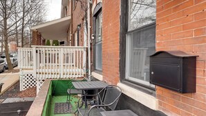 A small outdoor patio with a table and chairs, a white fence, and a mailbox on the building's side. - 1 Mi to Dtwn Wilmington: Convenient + Cozy Home! (Wilmington)