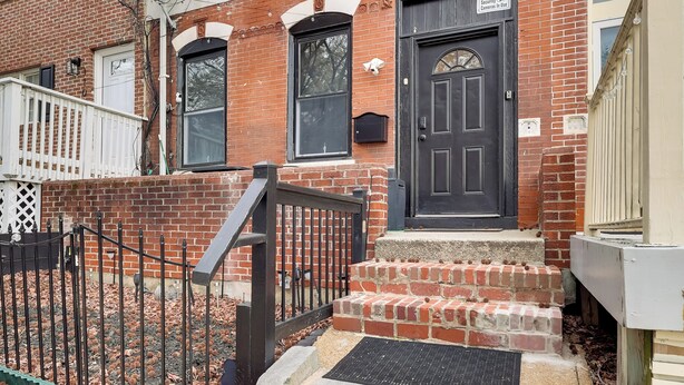A brick building with a black front door, a small porch, and a metal fence. - 1 Mi to Dtwn Wilmington: Convenient + Cozy Home! (Wilmington)
