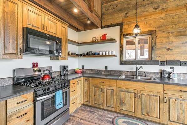 Une cuisine avec des meubles en bois, une cuisinière en acier inoxydable, un four à micro-ondes et un évier.