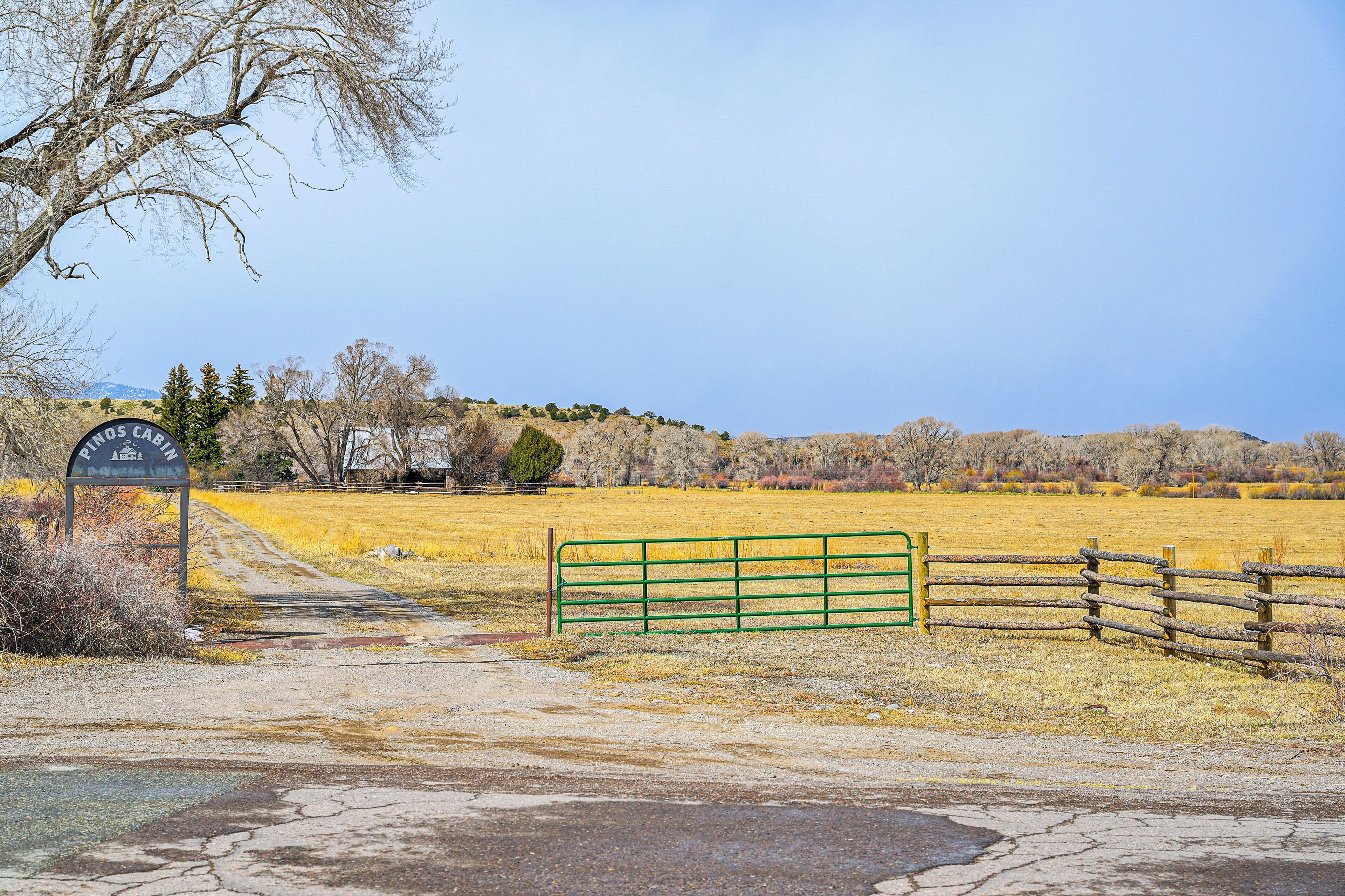 A rural road leading to a gate with a sign that reads "Los Cabos Paradise."