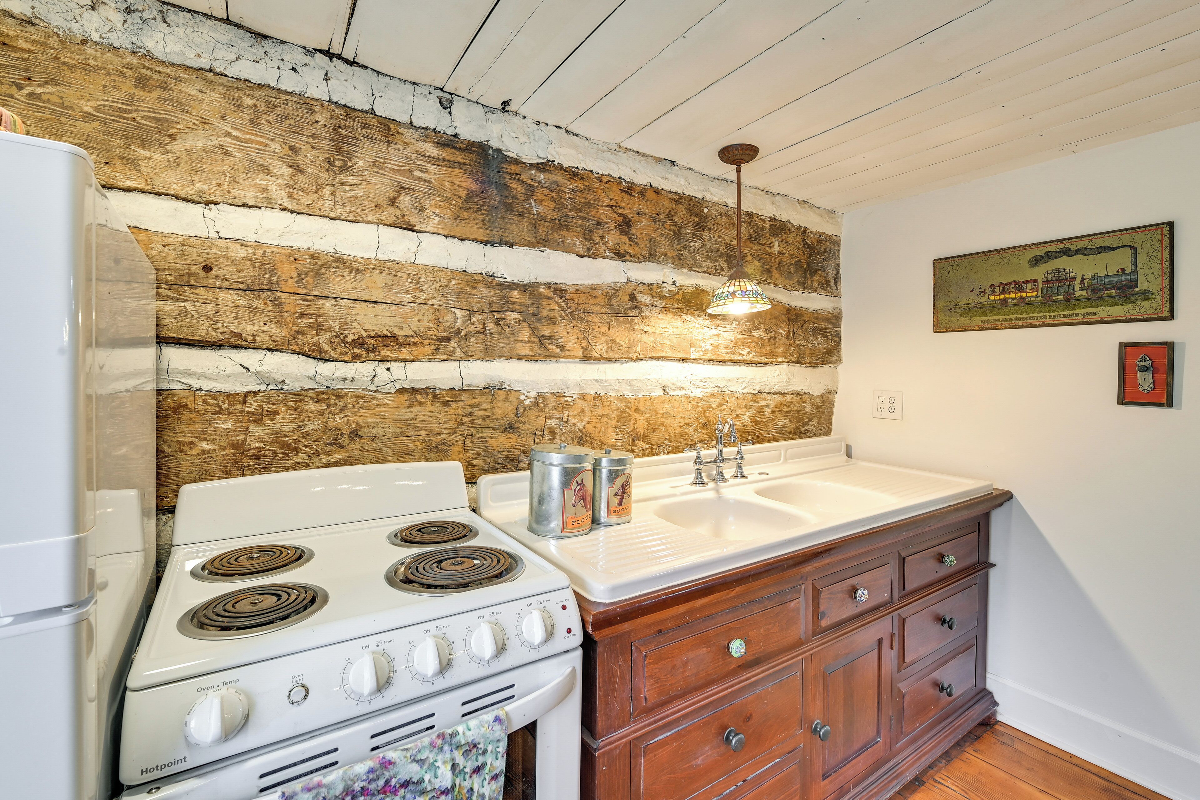 A kitchen with a wooden wall, a white stove, a sink, and wooden cabinets.