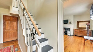 A staircase with white railings and wooden steps, leading to a room with a fireplace, a television, and a wooden dresser. - Georgetown Home Near Kentucky Horse Park! (Georgetown)
