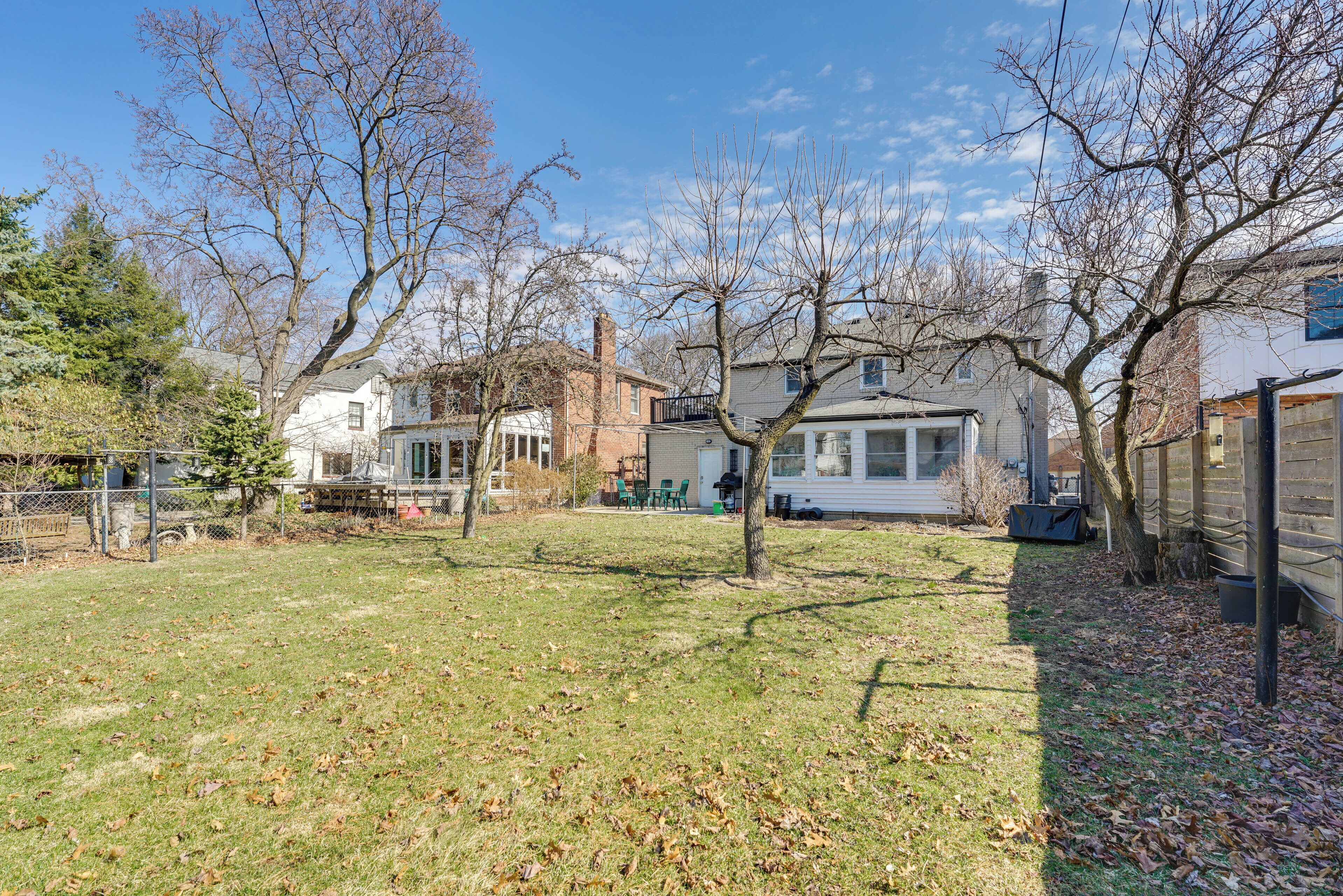 A residential area with houses, a grassy yard, and leaf-covered ground.