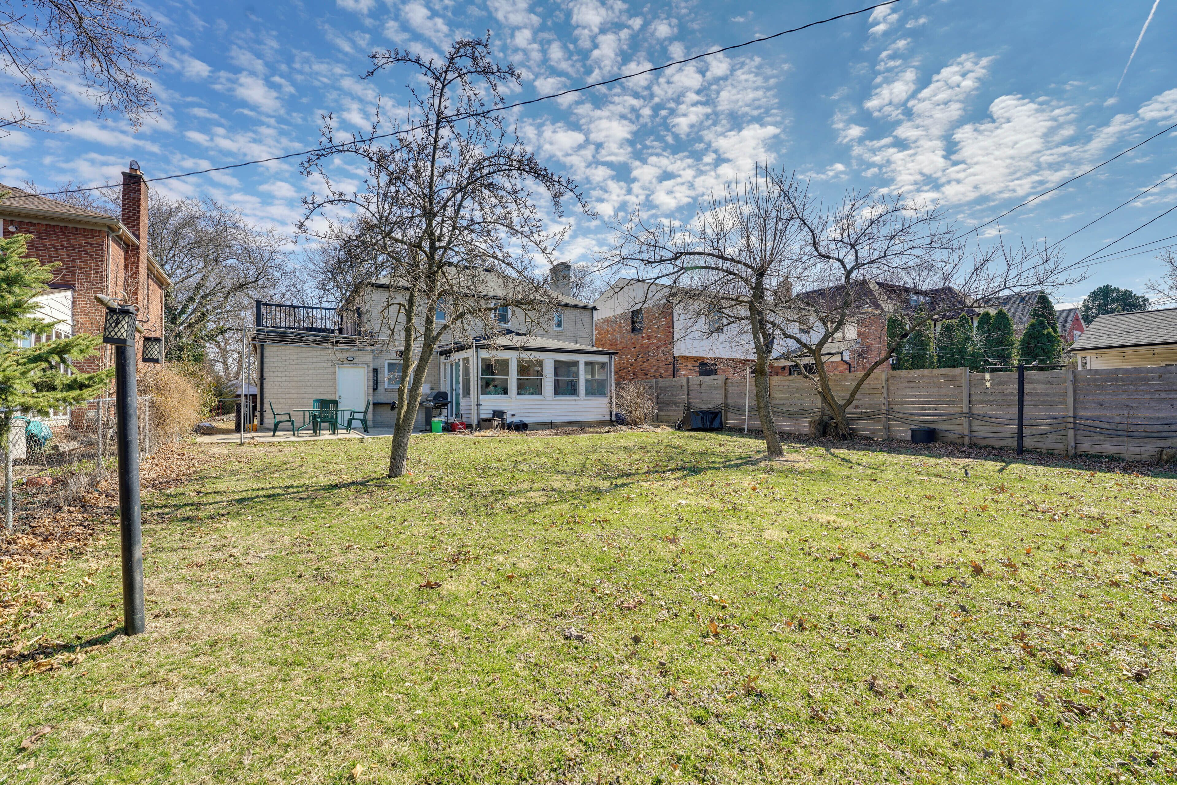 A residential backyard with a house, a fenced area, and a clear sky.
