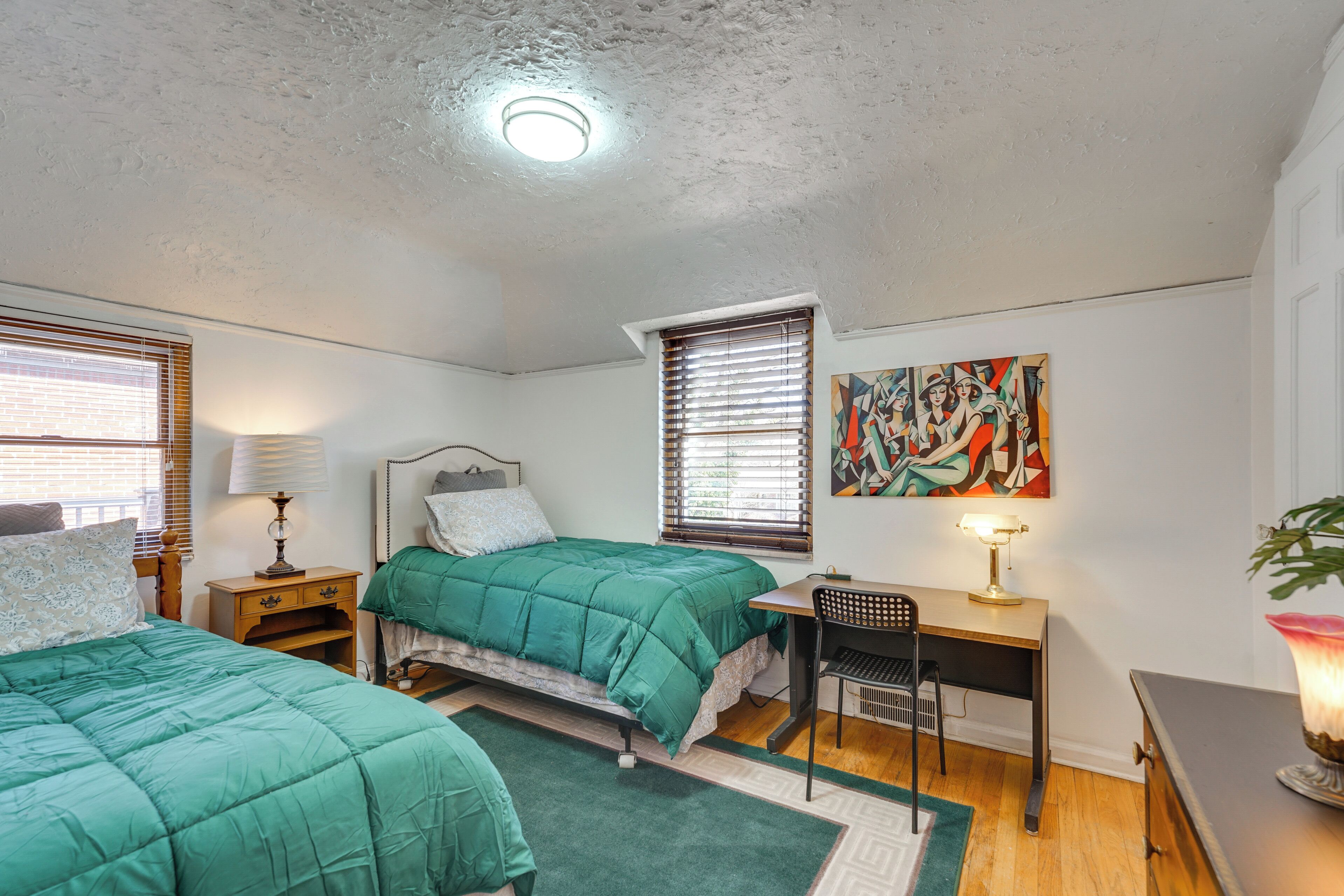 A bedroom with two beds, a desk, and a chair.