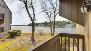 A wooden deck with a view of a lake and houses across the water. - Pinehurst Lake Condo: Water View & Community Perks (Pinehurst)