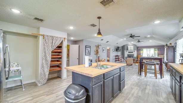 A spacious kitchen with a central island, wooden cabinets, and a modern ceiling fan. - Outdoorsy Getaway Near Atoka: Hunt, Fish & Relax! (Pittsburg)