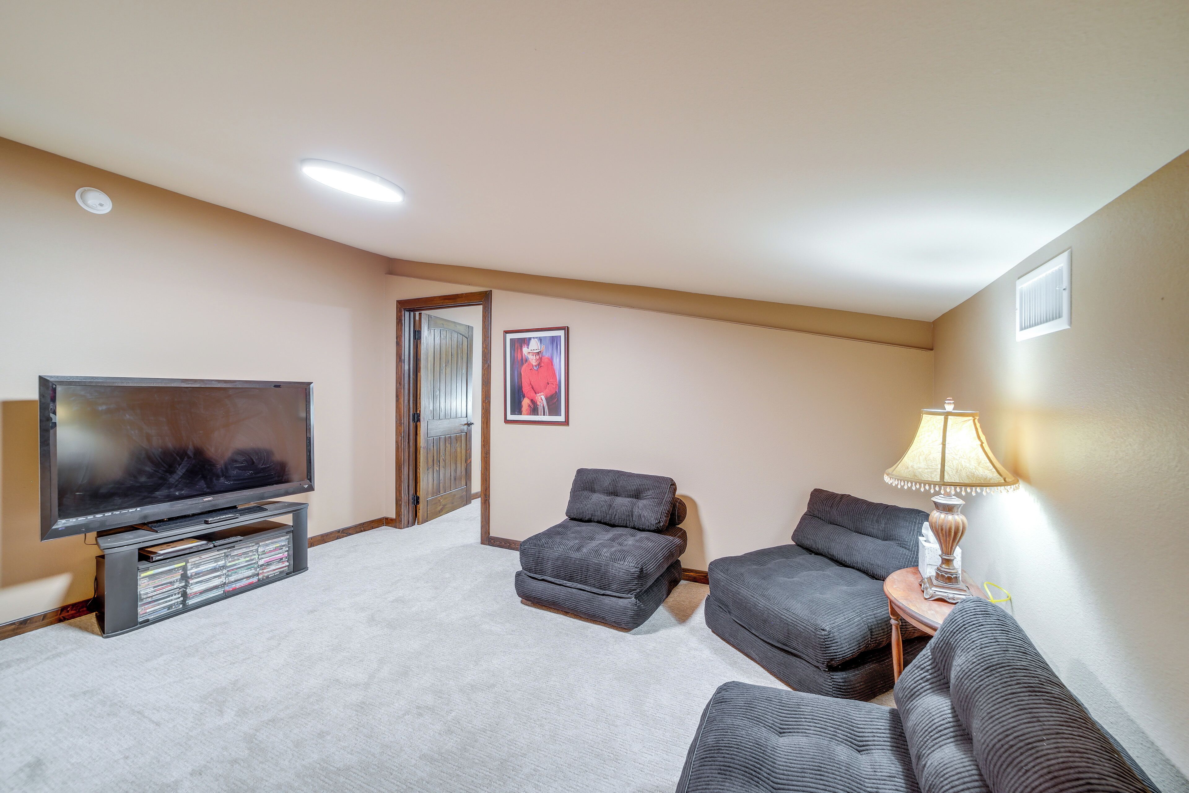 A living room with a flat-screen TV, two grey sofas, a small table with a lamp, and a picture on the wall.