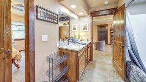 A bathroom with wooden cabinetry, a large mirror, and a vanity with a sink and towel rack.