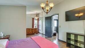 Ein Schlafzimmer mit einem großen Bett, einem Schminktisch, einem an der Wand montierten Fernseher und einer Chandelier.
