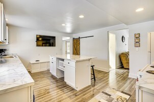 Una cocina moderna con armarios blancos, encimera de mármol y suelo de madera.