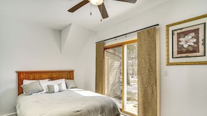 Una camera da letto con un letto, un ventilatore a soffitto e un'ampia finestra.