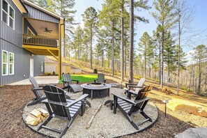 A deck with Adirondack chairs and a fire pit, surrounded by a forested area. - Gated Community w/ Perks: North Carolina Hideaway (Connellys Springs)