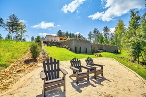 Ein sandiger Bereich mit Adirondack-Stühlen, einer Steinmauer und einem Gebäude mit Schrägdach im Hintergrund.