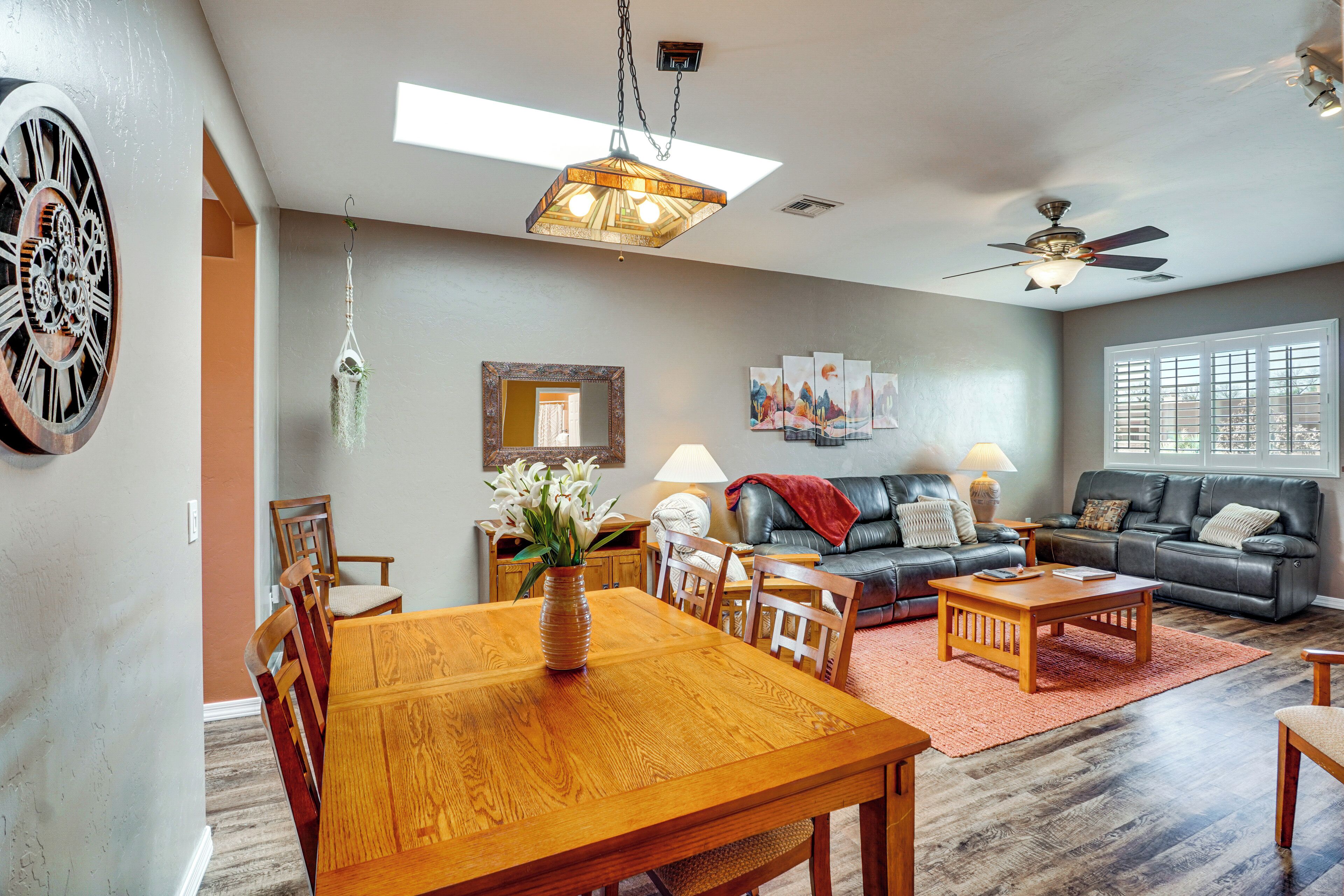 A spacious living room with a dining area, a sofa set, and a ceiling fan.