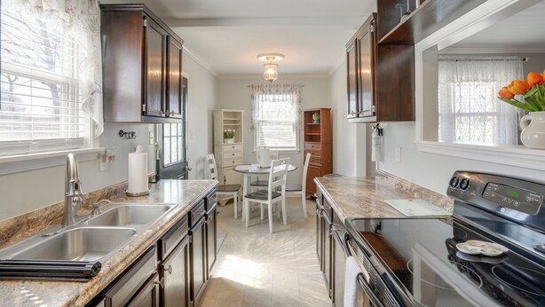 A kitchen with granite countertops, stainless steel appliances, and white cabinetry.