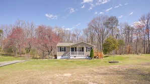 A single-story house with a front porch, surrounded by a grassy yard and trees.