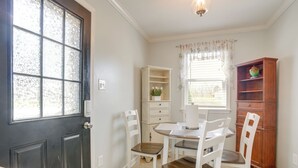 A dining area with a table and chairs, a cabinet, and a window with curtains.