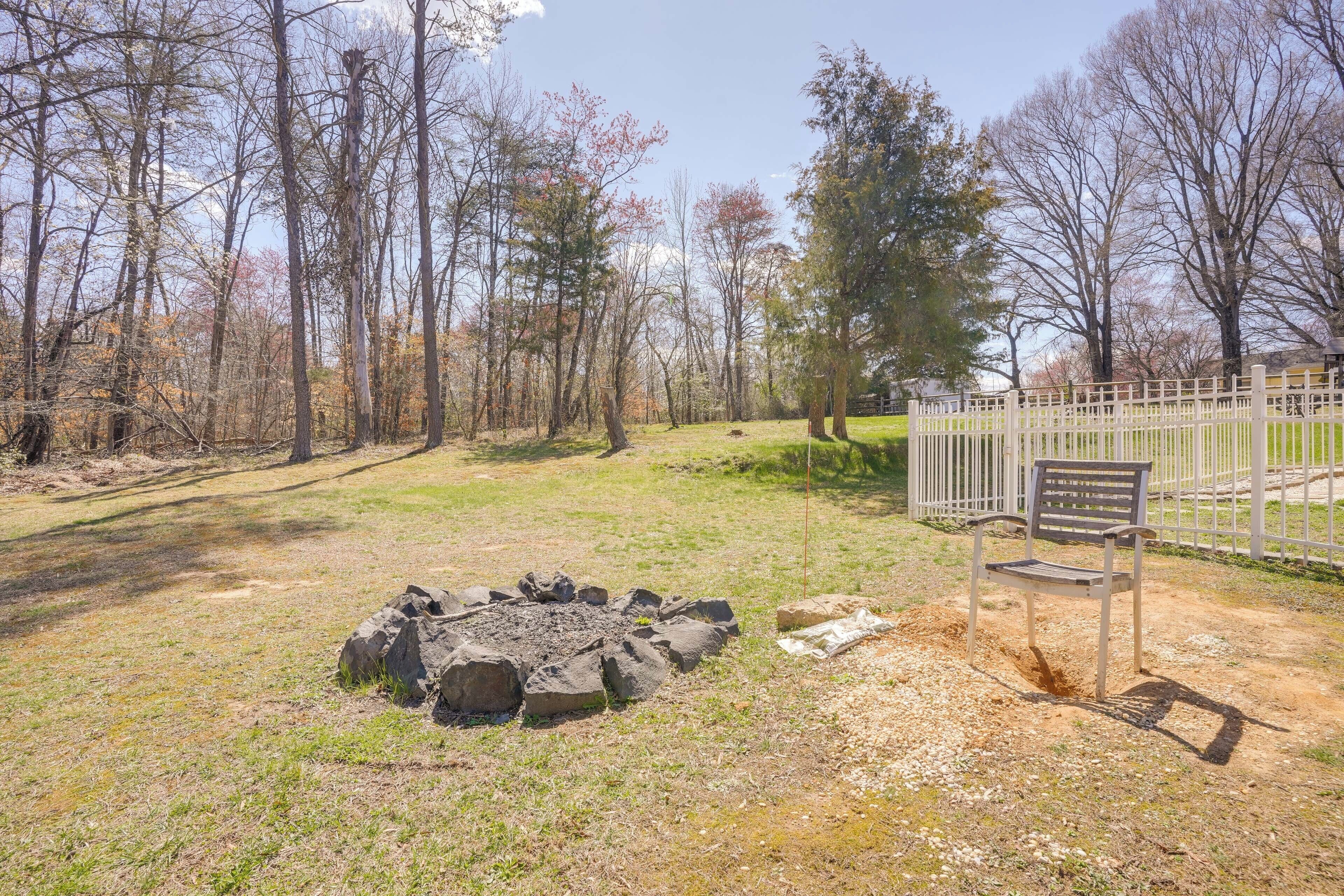 Un terrain de camping équipé d’un foyer, d’un banc et d’une zone délimitée par une clôture.