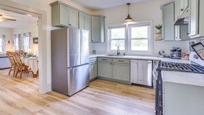 A modern kitchen with light green cabinets, stainless steel appliances, and a wooden floor. - Half-mi to Dtwn Lufkin: Charming & Spacious Home! (Lufkin)