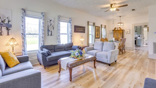 A spacious living room with a grey sectional sofa, a wooden coffee table with a floral centerpiece, and a dining area with a wooden table and chairs. - Half-mi to Dtwn Lufkin: Charming & Spacious Home! (Lufkin)