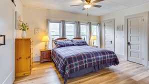 A bedroom with a bed, a ceiling fan, a nightstand with a lamp, and a wooden cabinet. - Half-mi to Dtwn Lufkin: Charming & Spacious Home! (Lufkin)