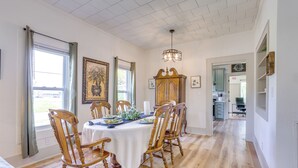 A dining area with a wooden table set for four, surrounded by wooden chairs, a chandelier, and artwork on the walls. - Half-mi to Dtwn Lufkin: Charming & Spacious Home! (Lufkin)