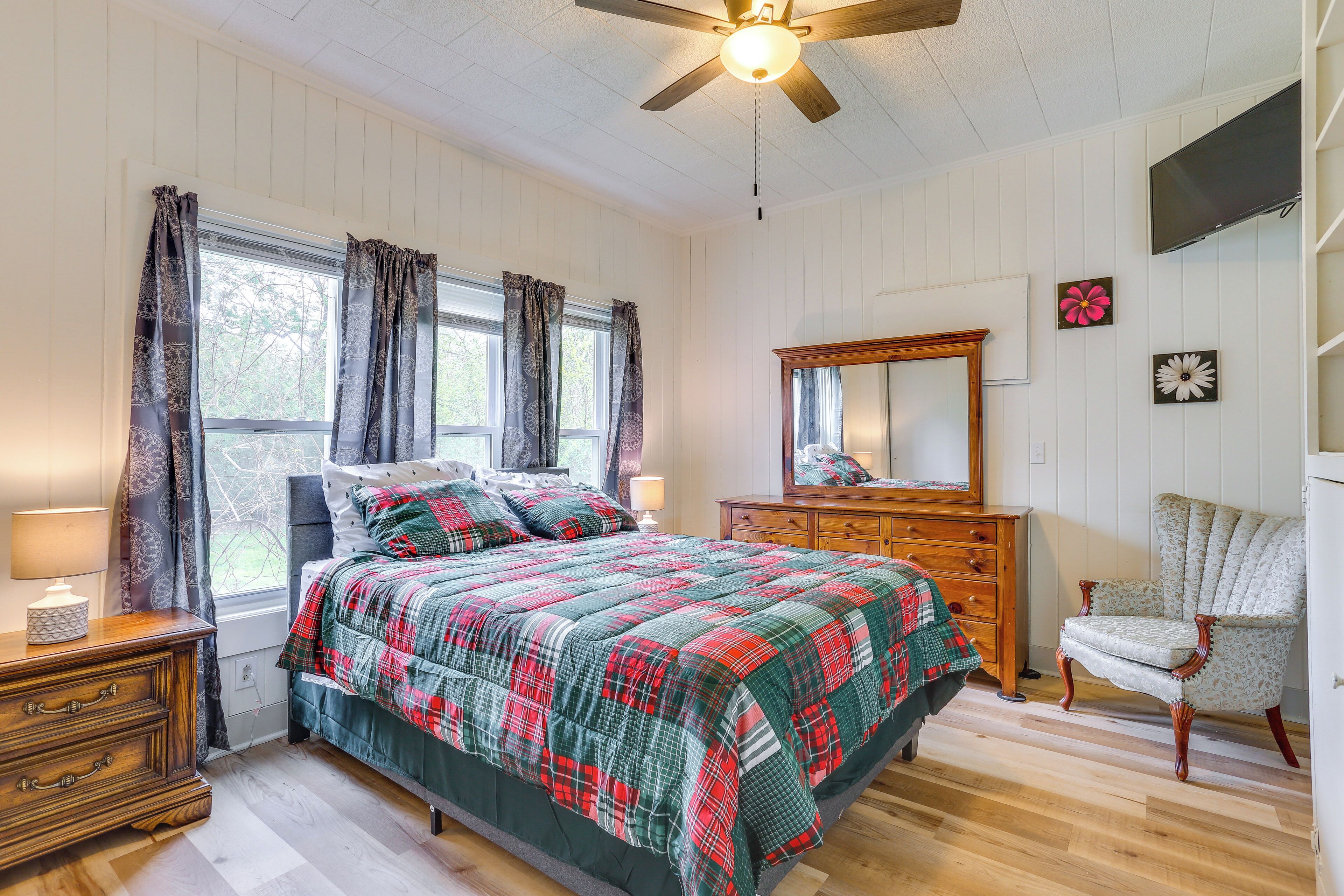 A bedroom with a bed, dresser, chair, and a ceiling fan.
