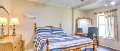 Un dormitorio con cama de madera, cómoda, espejo y ventilador de techo.
